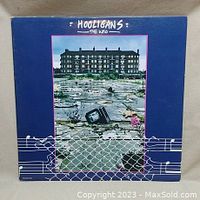 Front cover of 'Hooligans' double album by The Who, blue background with abandoned TV and fenced area photo.