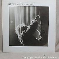 Front cover of the Wide Awake in America vinyl EP by U2, showing a blurred live performance photo in black and white.