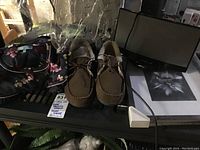 Photo showing items including floral black bag or night shirt, brown slippers size 9, Bose docking station, and picture frame.