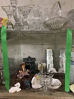Shelf with glass vases, goblets and bowls on top, lower shelf with ceramic and onyx figurines, motivational plaques.