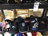 Wide view of eight baseball style hats arranged on a shelf showing various logos and colors.