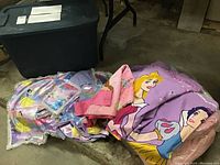 Photo showing folded Disney princess bedding including duvet cover and bedskirt featuring Aurora and Snow White characters.