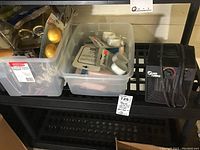 Plastic bins containing new plastic shower curtain hooks/rings and a black mini heater on a black surface.