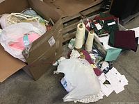 Wide view of all yarns, spools, fabric swatches, started knitting projects, and other crafting supplies spread on floor and in boxes