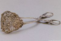 Front angled view of the vintage silver serving scissor pastry tong with detailed repousse work.