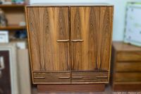 Front view of closed armoire doors and lower drawers with rosewood veneer grain