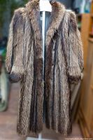 Full front view of the vintage long raccoon fur coat on a mannequin, showing fur texture and length.