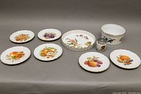 Full view of all plates and dishes showing fruit motifs and gold rim detailing