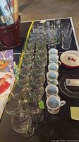 Wide view showing rows of glassware and mugs on table with some holiday plates
