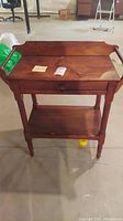 Wooden night stand shown full view with side towel holders and drawer.