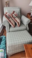 Full view of upholstered arm chair with pillows and matching ottoman
