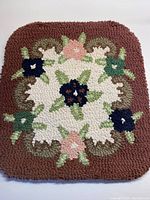 Full view of the hand hooked chair pad displaying floral and leafy design on cinnamon background.