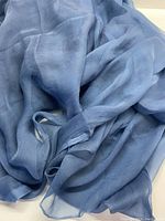 Close-up photo showing the lightweight, sheer blue-grey chiffon fabric with soft folds and natural draping.