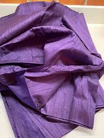 Folded length of rich fuchsia purple raw silk fabric showing subtle texture and sheen.