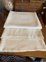 Folded Kenwood blanket on wooden table showing creamy color and blanket stitch edges.