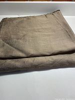 Folded piece of coffee colored raw silk fabric showing the texture and color of the material.