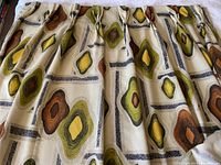 Full view of one cream-colored drapery panel featuring abstract diamond motifs in cinnamon, lime green and amber.
