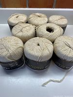 Overview of eight balls of yarn placed closely together, all wrapped with labels.