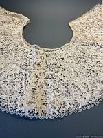 Close-up of the handmade lace neckline area showing fine detail and scalloped edges.