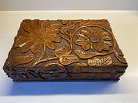Top view showing carved floral and fauna patterns with prominent flowers and leaves on lid