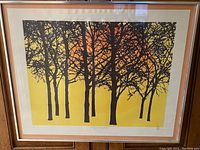 Framed art print showing silhouetted apple tree branches with yellow to amber background and tangerine sun.
