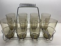 Front view of all 8 smoky glass tumblers arranged in the chrome wire stand showing the uniform size and coloring.