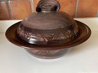 Front angled view of the lidded clay vessel showing geometric trim and glaze colors