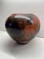 Front angle showing the full rounded body of the clay vessel with black splash patterns.