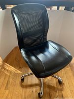 Front angled view of black office chair showing cushioned seat and mesh backrest.