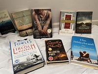 Top view of 9 books arranged side by side, front covers visible, showing various titles and authors.