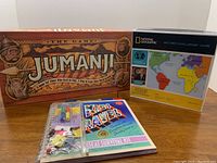 Photo showing Jumanji board game box, National Geographic Geo Bee Challenge Game box, and Kids Travel Survival Kit laid out side by side.