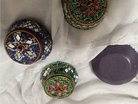Top view of four small decorative round boxes with intricate mirror and bead embellishments. Two green and two blue boxes, each with a patterned lid.