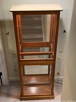 Front view of the full wooden curio cabinet with glass doors open, showing empty interior and unfinished wood top.