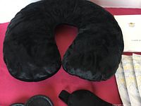 Black U-shaped inflatable travel pillow with soft cover on red background