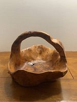 Front view of the wooden bowl showing the carved handle and natural edge detail.