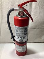 Full view of the red 5lb ABC dry chemical fire extinguisher with instruction label and hose.