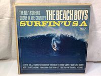 Front cover of The Beach Boys Surfin' USA album sleeve showing title and a surfer on a wave.