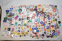 Overview of the large collection of vintage and retro button pins laid out on a table showing diverse colors, shapes, and designs
