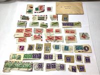 Various used US postage stamps from 1947 arranged on a white surface, including multiple denominations and some airmail stamps.