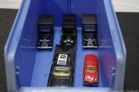 Top down view inside blue bin showing three blue and two other colored vintage die cast toy cars