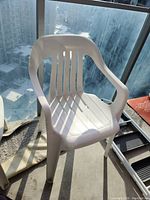 White plastic lawn chair seen from a slightly angled front view.