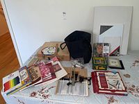 Overview of all items on a bed including canvases, brushes, bags, books, and paint tubes.