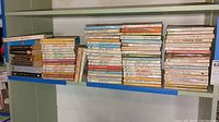 Books arranged on shelf showing spines and titles including Charlotte Lamb, Rachel Lindsay, Janet Dailey, Violet Winspear and others.