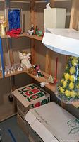 Shelves showing angel figurines, red bows, nativity figures and boxed items beneath.