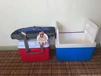 Two hard coolers, one blue and white, the other red and white with black lid and handle.