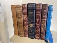 All seven Franklin Library books lined up, showing covers and spines with distinct titles and gold embellishments.