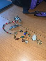 Overview of entire lot on wood surface including rings, bracelet, earrings, pins and pendants