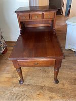 Front and top view of one Pennsylvania House side table showing three drawers, wooden finish, and turned legs on wooden floor.