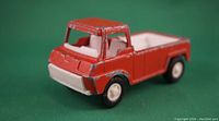 Red vintage Tootsie Toy pickup truck showing front and side with paint wear.