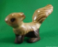 Front side view of the miniature glazed pottery squirrel figurine showing the head, body, and raised tail with detailed texture and colors.